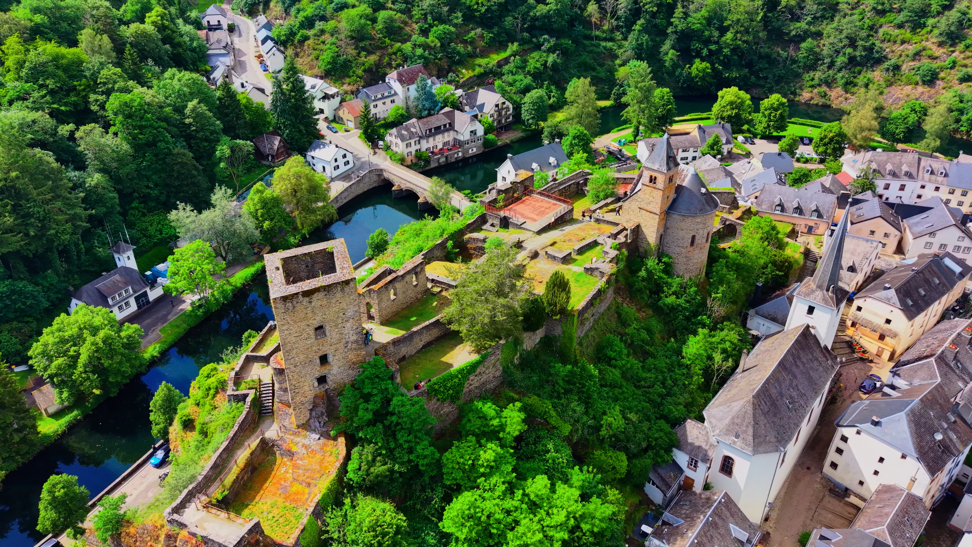The twelfth-century keep from low altitude. The curtain wall, the watchtower, the roofless chapel — and below it, the village and the river it commanded. Three centuries of holding this valley, then a gradual abandonment the forest accepted on its own terms.