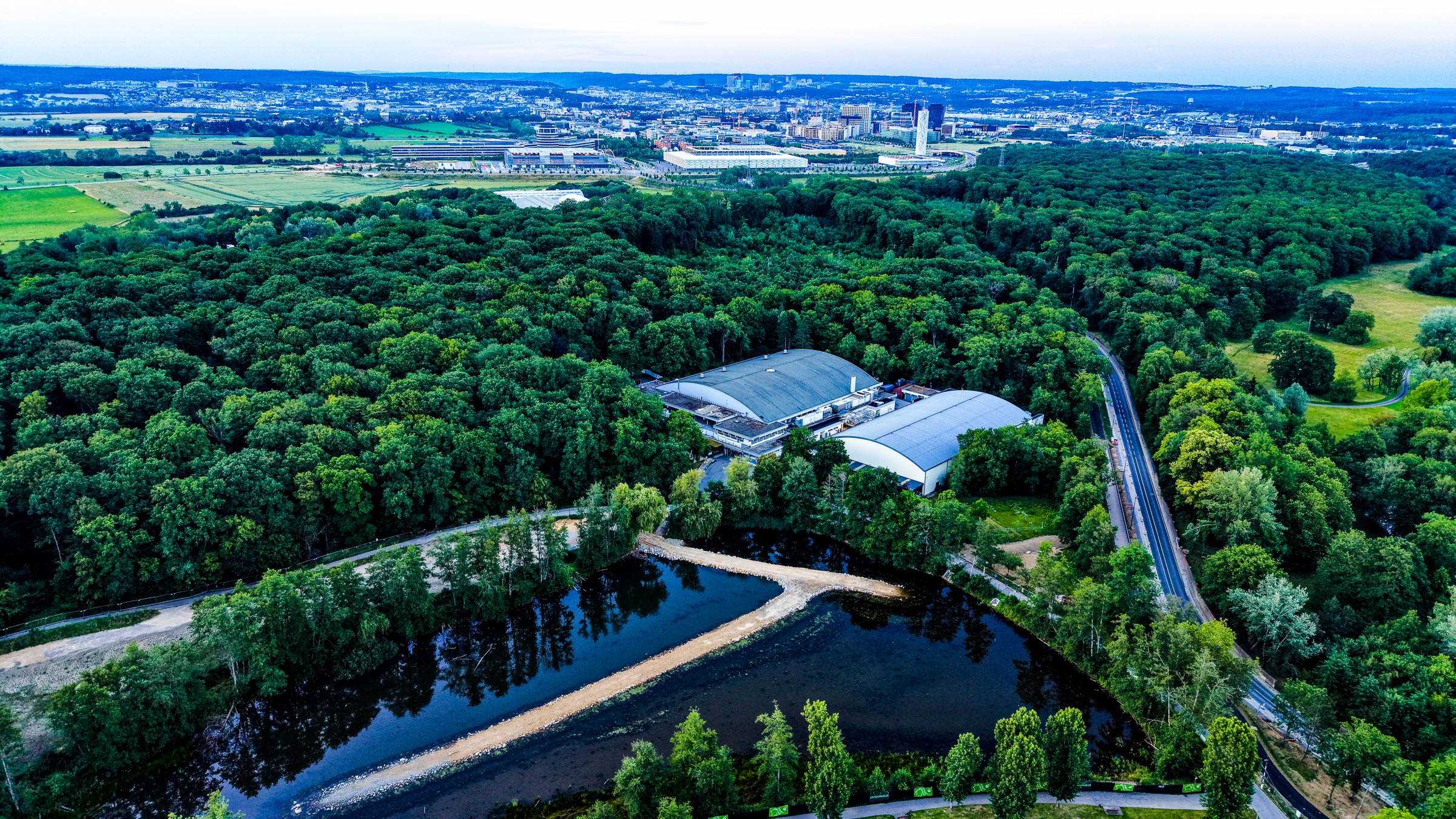 Park and lake in their landscape context — open ground on one side, the city pressing in on the other.