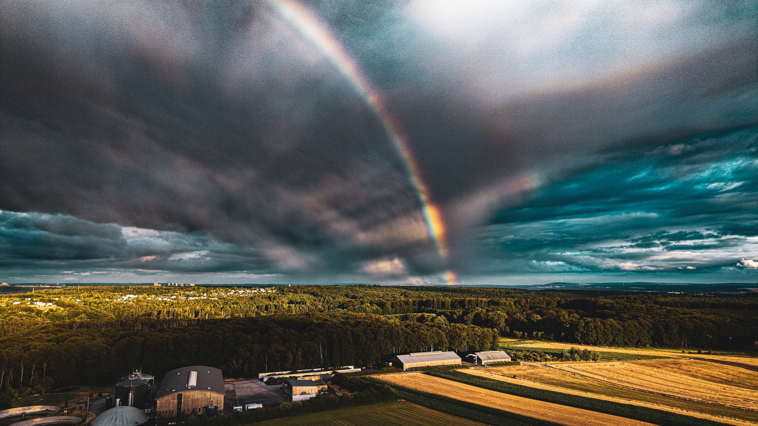 A double rainbow arcing over dark storm clouds and farmland at Marienthal