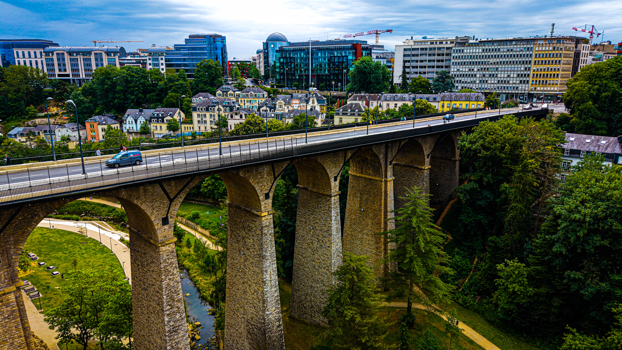 The Passerelle from the side — the full height of the pillars visible, the Alzette below, the residential quarter of Hollerich above. 290 metres of viaduct that solved a geography problem and then became a landmark.