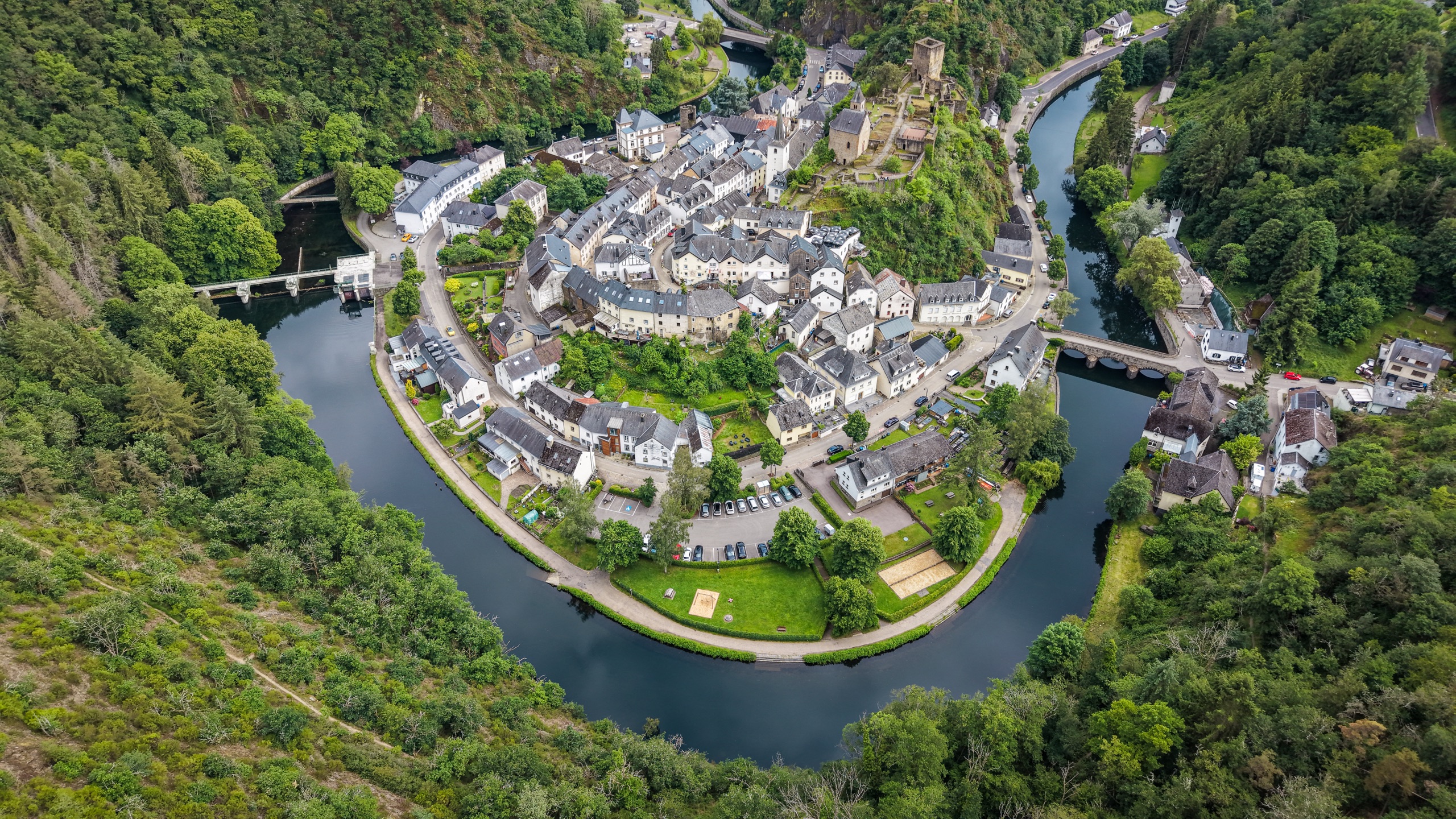The village of Esch-sur-Sûre inside the river bend. Three sides enclosed by the Sûre. The geometry is obvious from altitude and invisible from the ground.